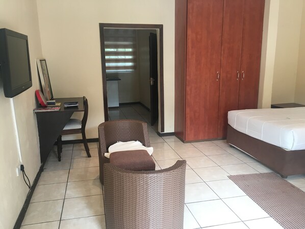 A hotel room with a bed, a desk with a chair, a wardrobe, and a television on the wall.
