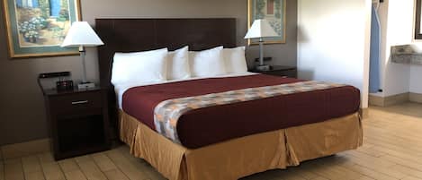 Ein Hotelzimmer mit einem großen Bett, zwei Nachttischen, zwei Lampen und zwei gerahmten Bildern an den Wänden.