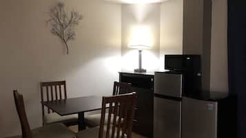 Una cocina compacta con una mesa y sillas, un refrigerador, un microondas y una lámpara de pared.