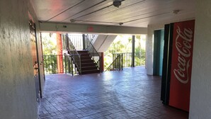 A spacious indoor area with a tiled floor, a staircase leading to an outdoor area, and a Coca-Cola sign on the wall. - Sun Coast Inn (Englewood)