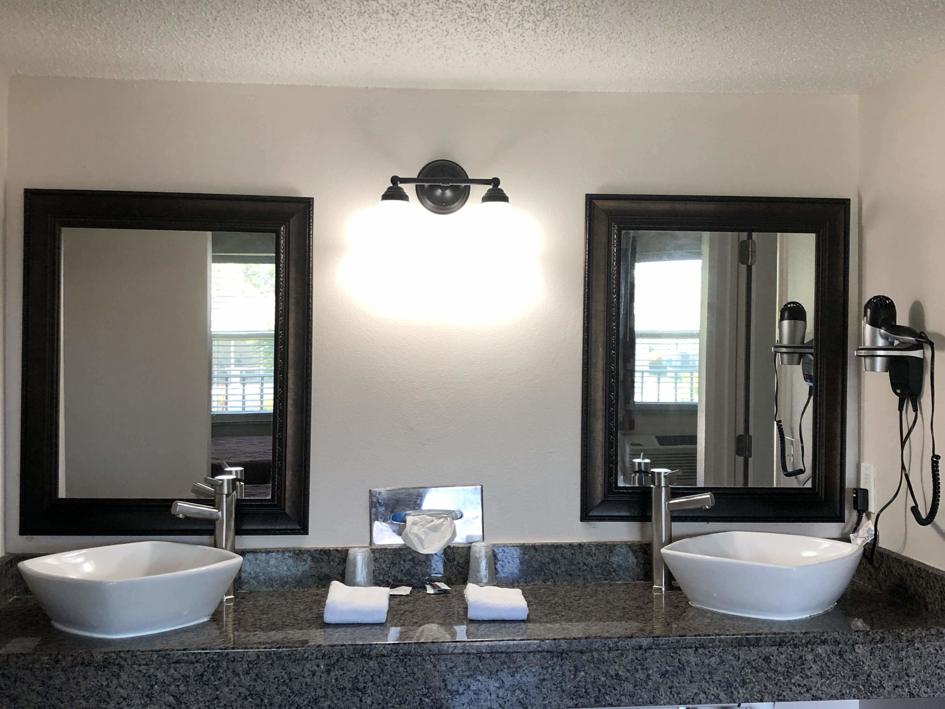 Un bagno con due lavandini, uno specchio grande e un asciugacapelli montato a parete.