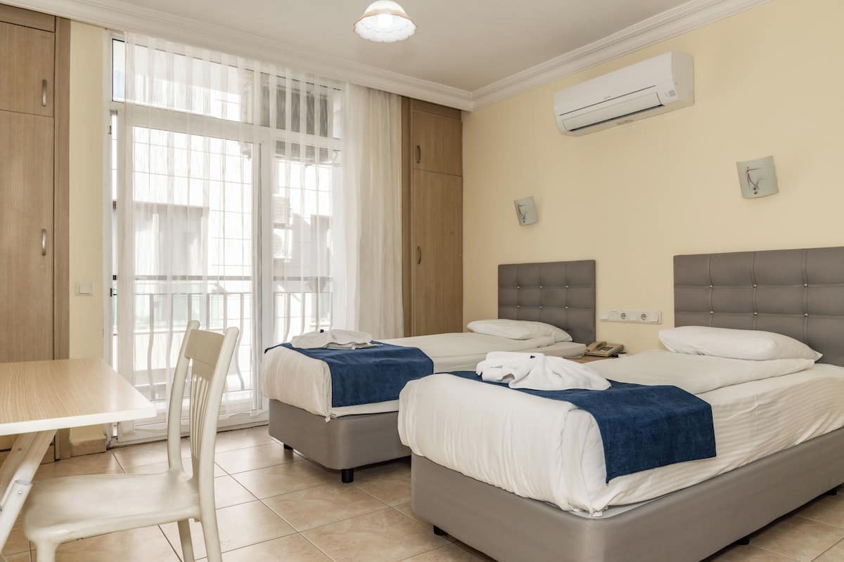 Quarto de hotel com duas camas, uma mesa de jantar e uma cadeira.