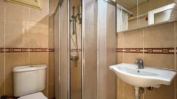Un baño con inodoro, cabina de ducha y lavamanos.