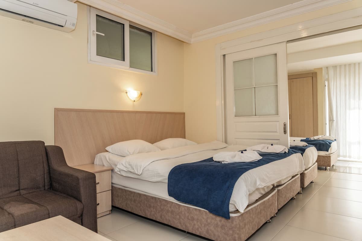 Quarto de hotel com uma cama grande, uma mesa de cabeceira, uma cadeira e uma janela.