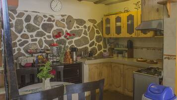 Una cocina rústica con paredes de piedra, armarios de madera y una estufa a gas.