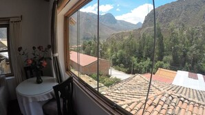 Una habitación con un ventanal amplio que ofrece vistas a campos escalonados y montañas.