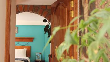 Un dormitorio con puerta de madera, una cama con ropa blanca, una mesita de noche y una pared azul.