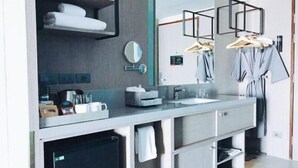 Un baño moderno con encimera gris, un espejo, un perchero y una toalla colgada en la pared.