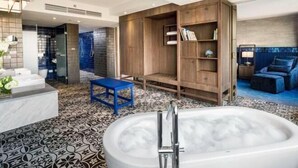 Un baño moderno con una bañera grande, un tocador de madera y un taburete azul.