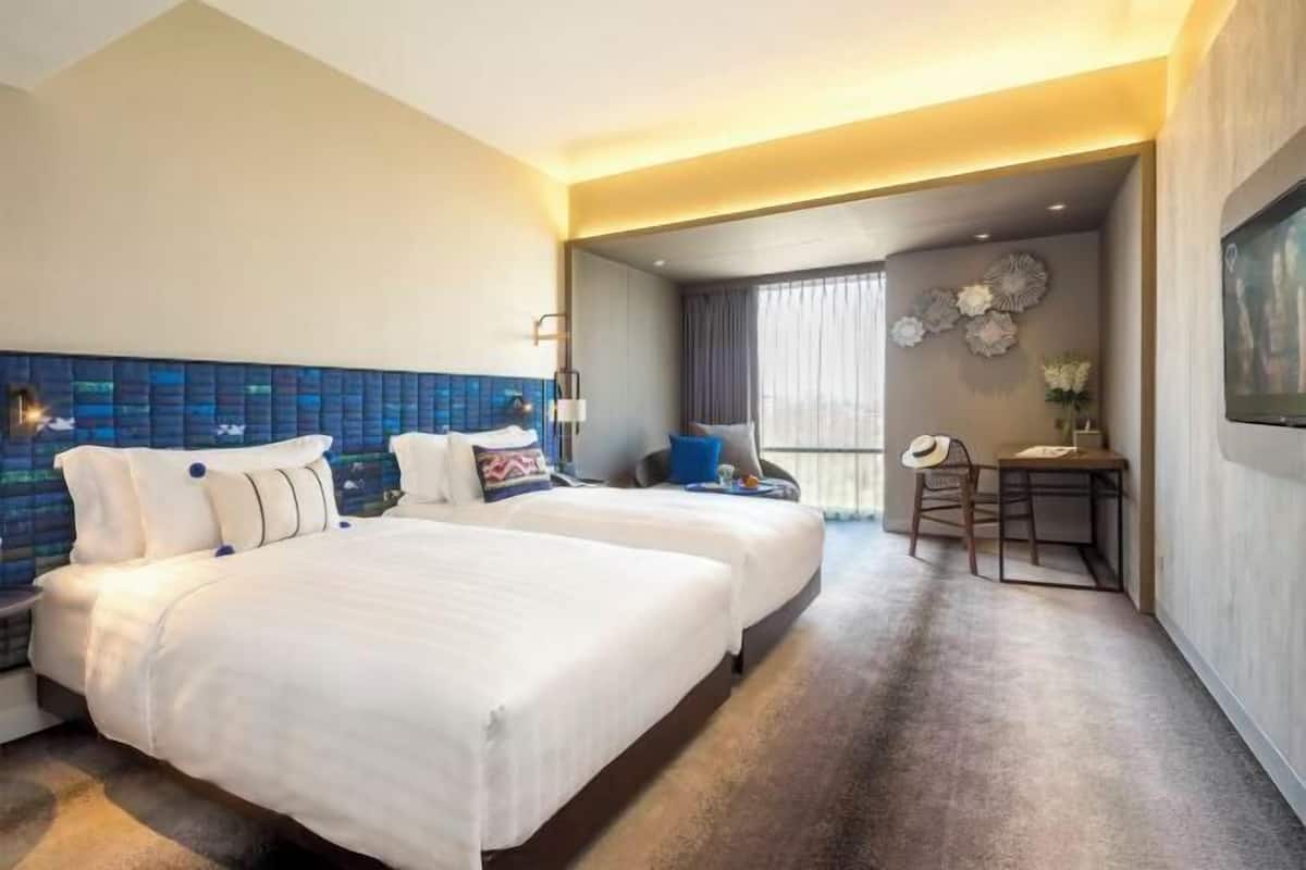 Une chambre d’hôtel avec deux lits, un bureau et une chaise.