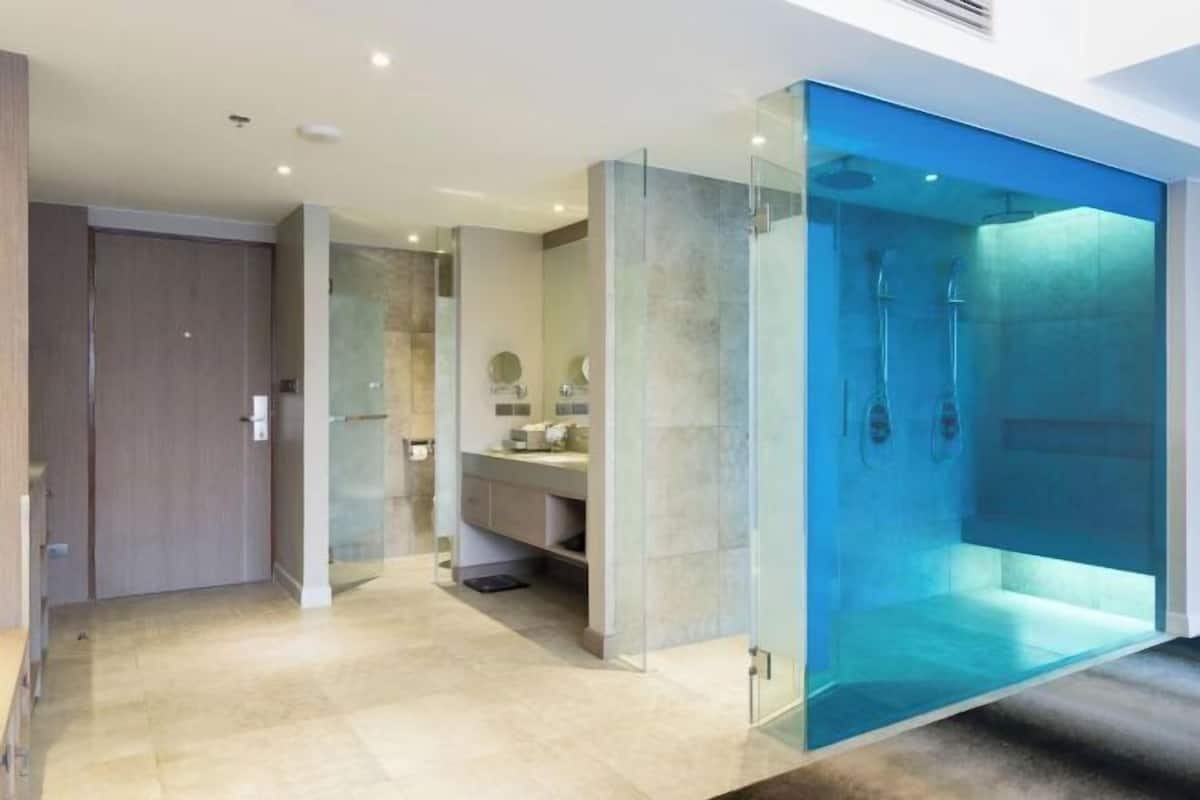 Une salle de bain moderne avec une douche à parois de verre, un meuble-lavabo avec un miroir et une porte donnant sur une autre pièce.