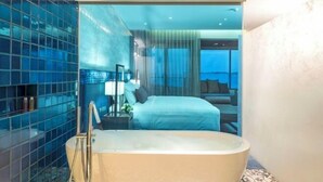 Un baño moderno con una bañera independiente, cabina de ducha con mampara de vidrio y un amplio ventanal con vistas a la ciudad.