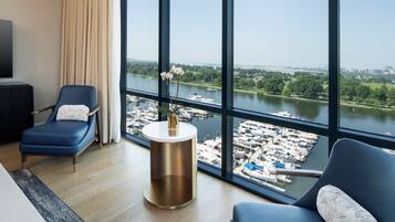 A modern hotel room with a large window offering a view of a marina and city skyline.