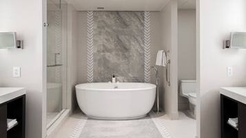 A modern bathroom with a freestanding bathtub, glass shower enclosure, and a herringbone-patterned wall.