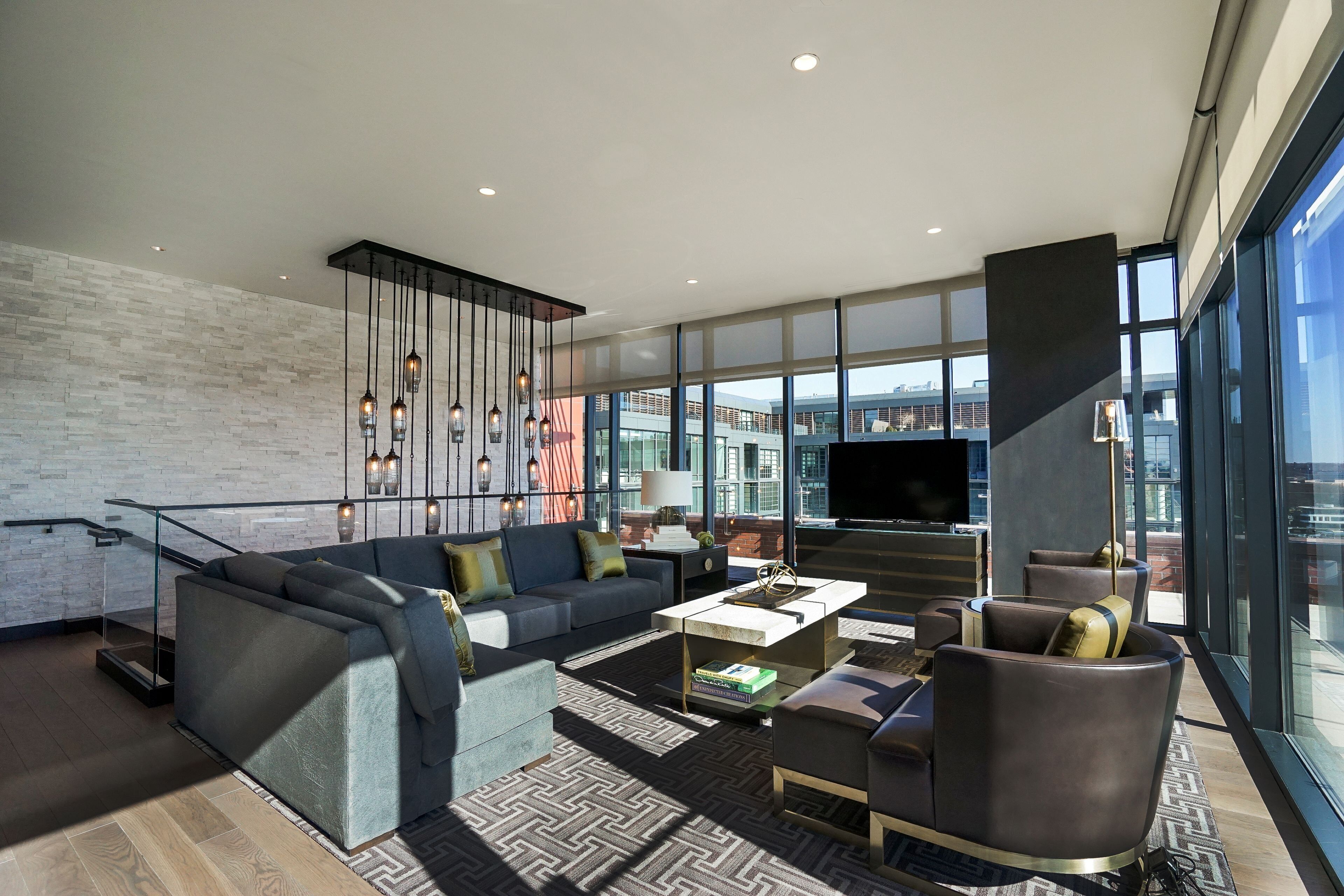 Un salon moderne avec un canapé, des fauteuils, une table basse et un téléviseur.