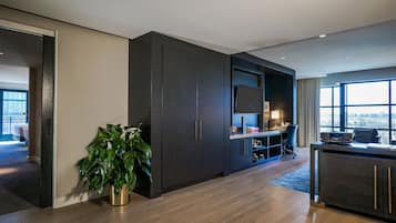 A modern hotel room with a large desk, a flat-screen TV, and a view of the city.