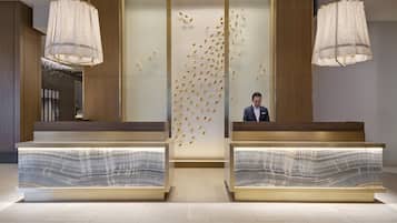A reception area with two reception desks, a wall with a bird decoration, and hanging lamps.