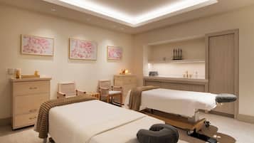 Een moderne hotelkamer met twee bedden, een massagetafel, een bureau en een kaptafel met planken.
