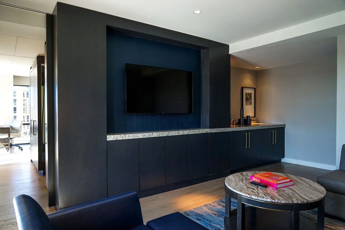 A modern living room with a flat-screen TV, dark cabinetry, a round coffee table, and a sofa.