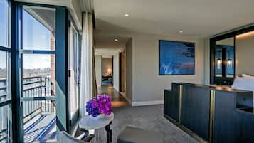 A hotel room with a view of the city, a large window, a seating area, and a modern bathroom.