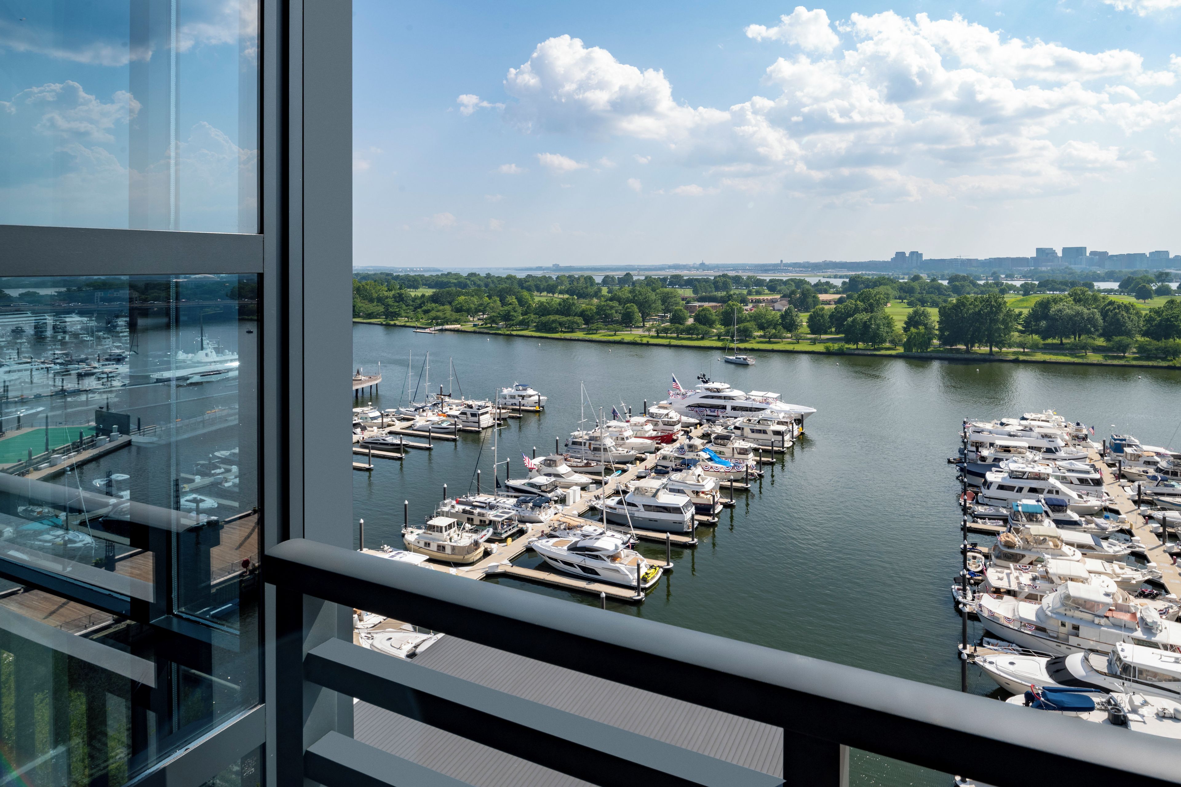 A marina with numerous boats docked, a clear sky, and a view of a city skyline in the distance.