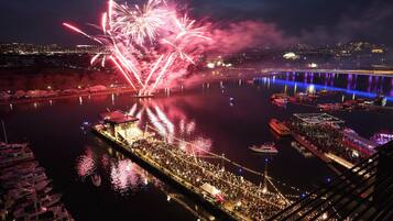 Uma área à beira-mar com barcos, pessoas e fogos de artifício.