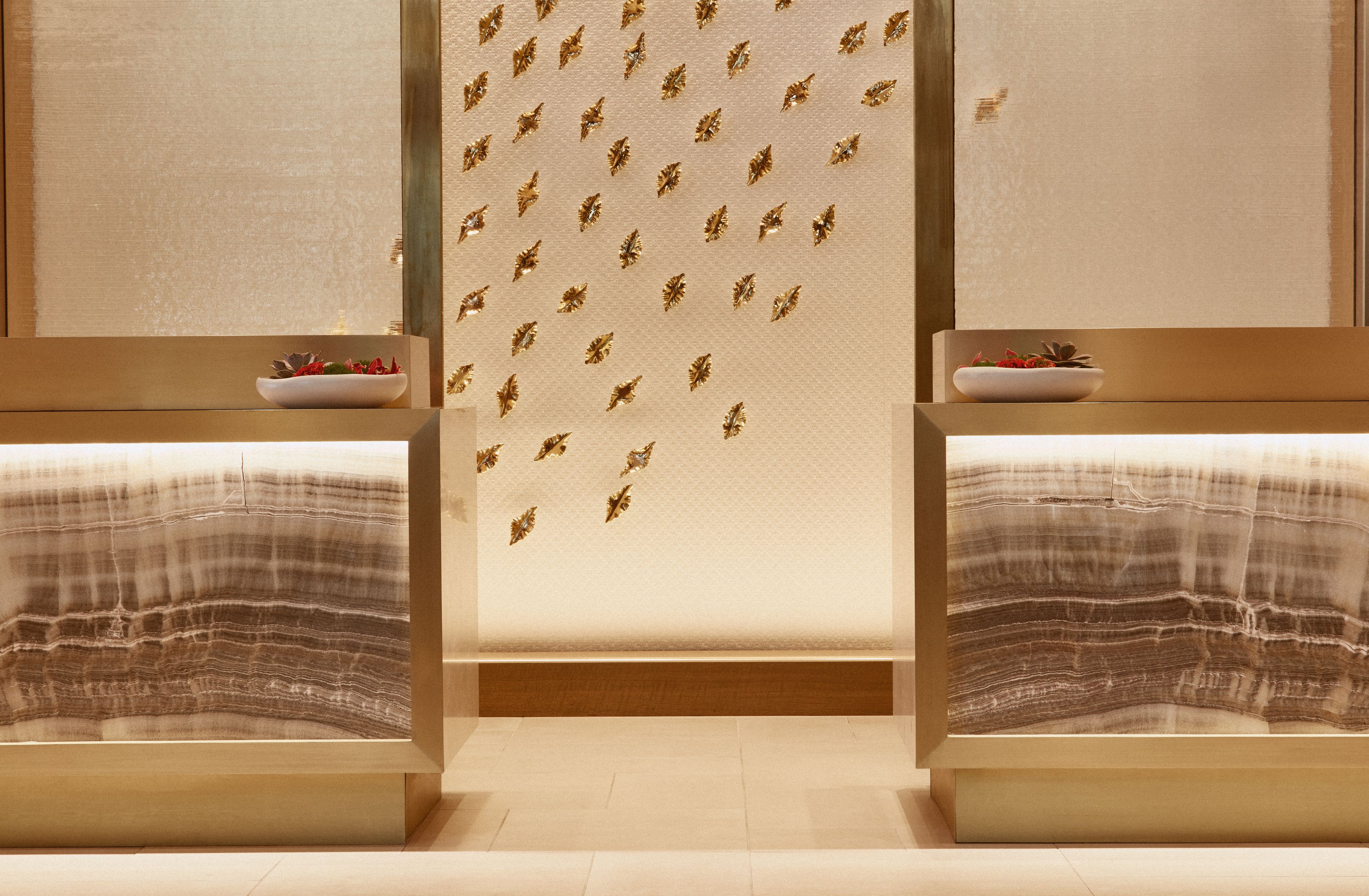 A hotel room with two beds, a decorative wall, and a small table with a bowl of fruit.