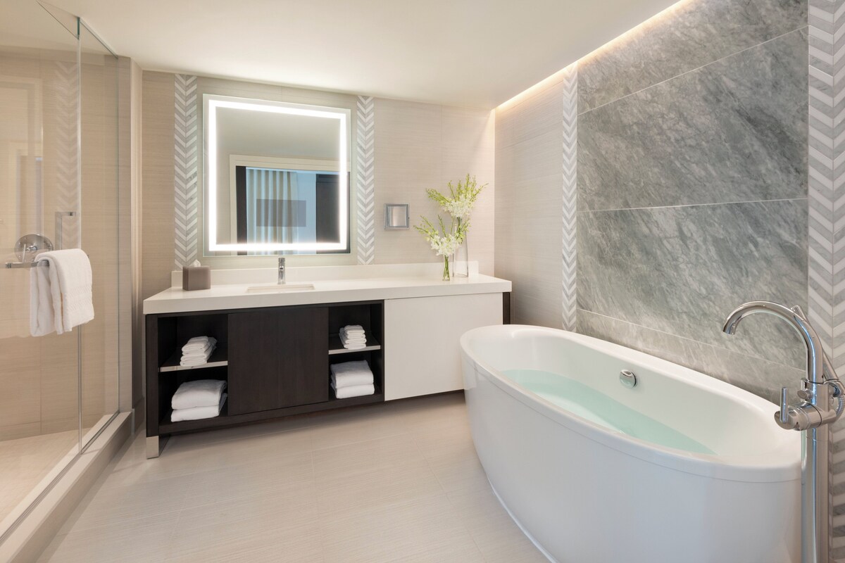 A modern bathroom with a freestanding bathtub, a vanity with a mirror, and a shower area.