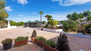 Un patio con plantas en macetas, un pabellón y una palmera.