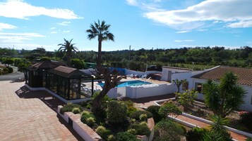 Zona residencial con piscina, palmeras y un pabellón.