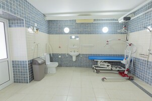 A bathroom with a toilet, sink, and a medical examination table.