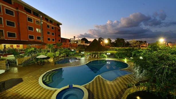 Un hotel con piscina, asientos al aire libre y fachada de color rojo.