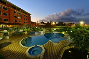 Un hotel con piscina, asientos al aire libre y fachada de color rojo.