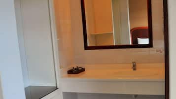 A bathroom with a white sink, a mirror with lights above it, and a white tiled floor.