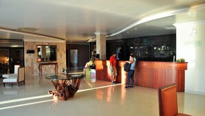 Un vestíbulo de hotel con una mesa de recepción, una mesa de vidrio y un árbol de Navidad.