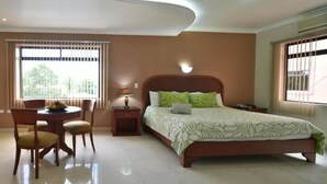 Un dormitorio con cama, escritorio, sillas, lámpara y ventana con persianas.