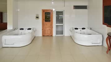 Two tubs flank a central doorway in this modern bathroom, surrounded by a tiled space with a wooden door and window.