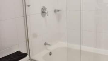 A bathroom with a toilet, a bathtub, and a shower enclosure.