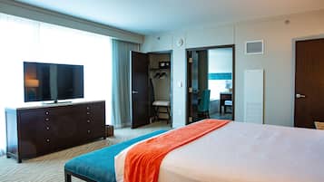 A hotel room with a bed, a television, a dresser, and a desk.