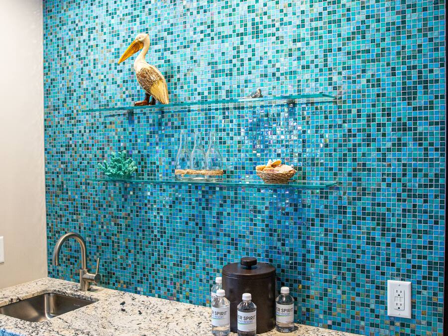 A bathroom with a mosaic tile wall, a sink, and a coffee maker.
