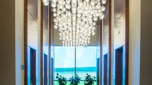 Ein moderner Flur mit einem einzigartigen, kugelförmigen Chandelier, Zimmerpflanzen und Blick ins Freie.