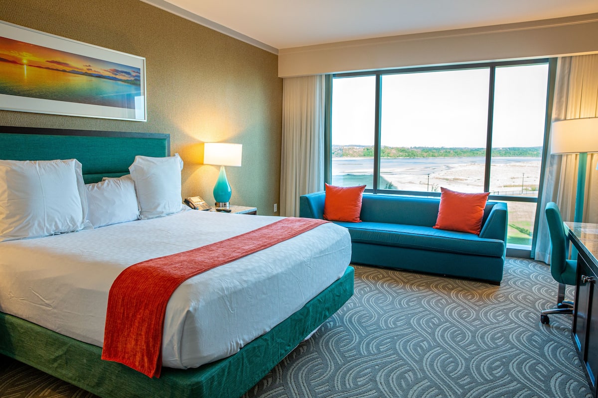 Ein Hotelzimmer mit einem großen Bett, einer Couch, einem Schreibtisch und Blick aufs Meer.