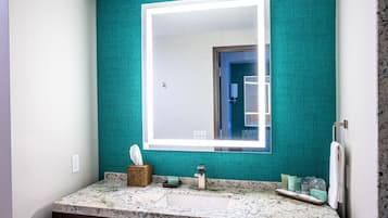 A bathroom with a teal wall, a white sink, and a large mirror.
