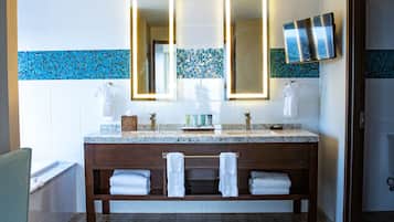 A bathroom with a wooden vanity, two mirrors, a sink, and a shower area.