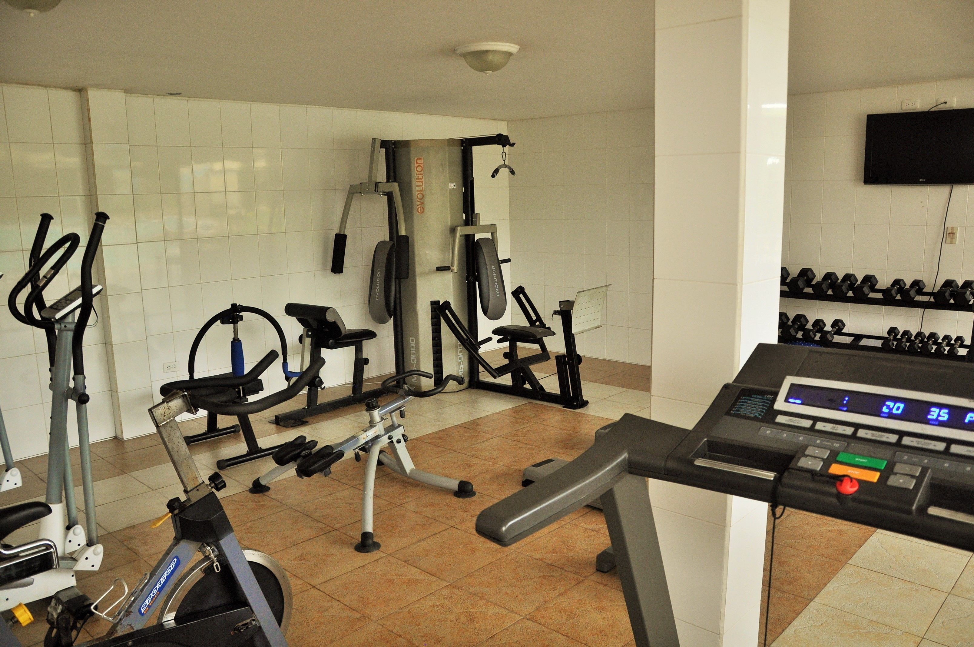 Ein Fitnessstudio mit verschiedenen Trainingsgeräten, darunter Laufbänder, Ergometer und Kraftgeräte.