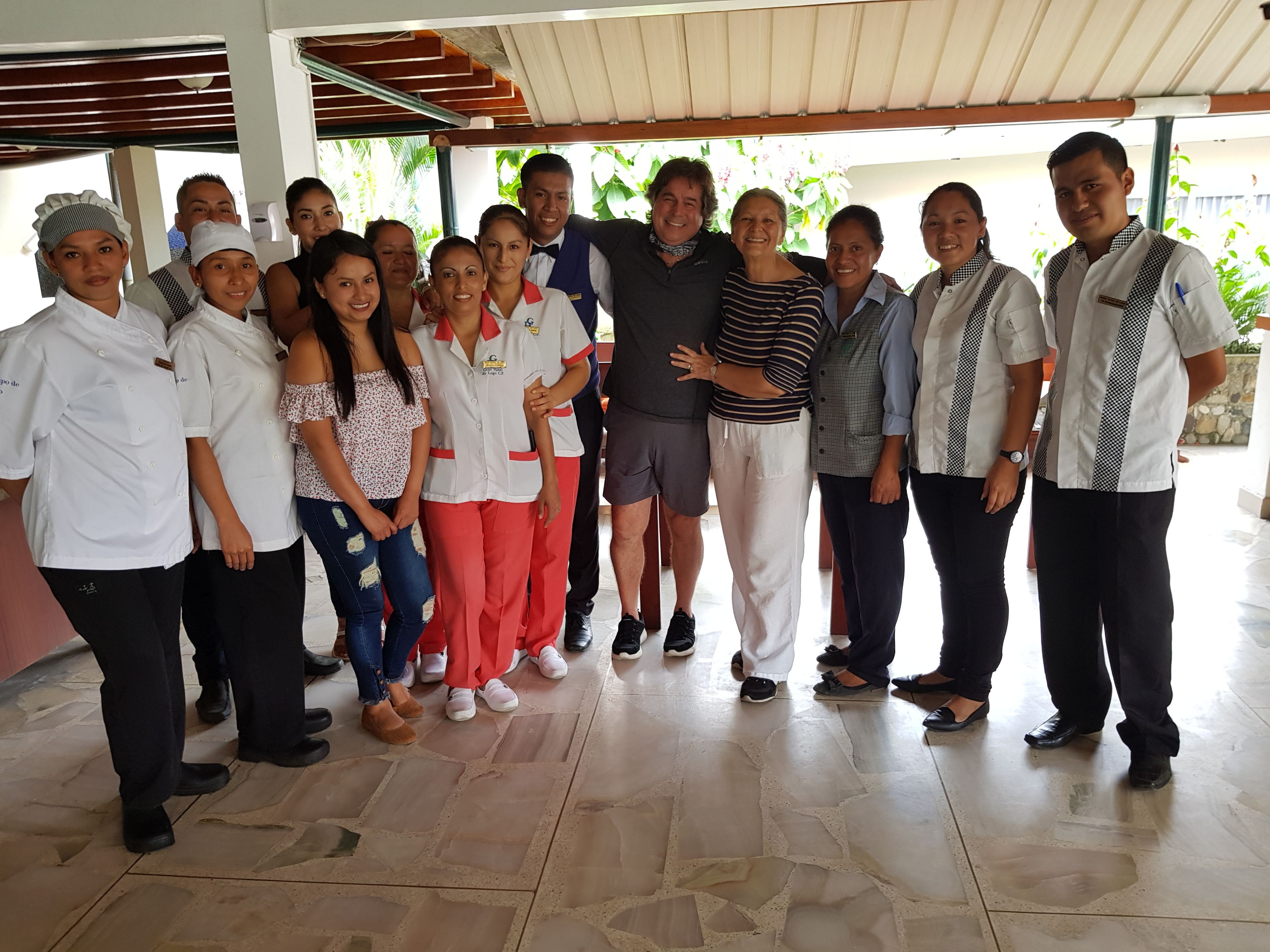A group of people standing in a covered outdoor area with a tiled floor.
