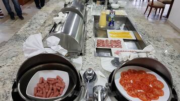 Un buffet proposant une variété d’aliments, notamment des saucisses, des tomates et du fromage.