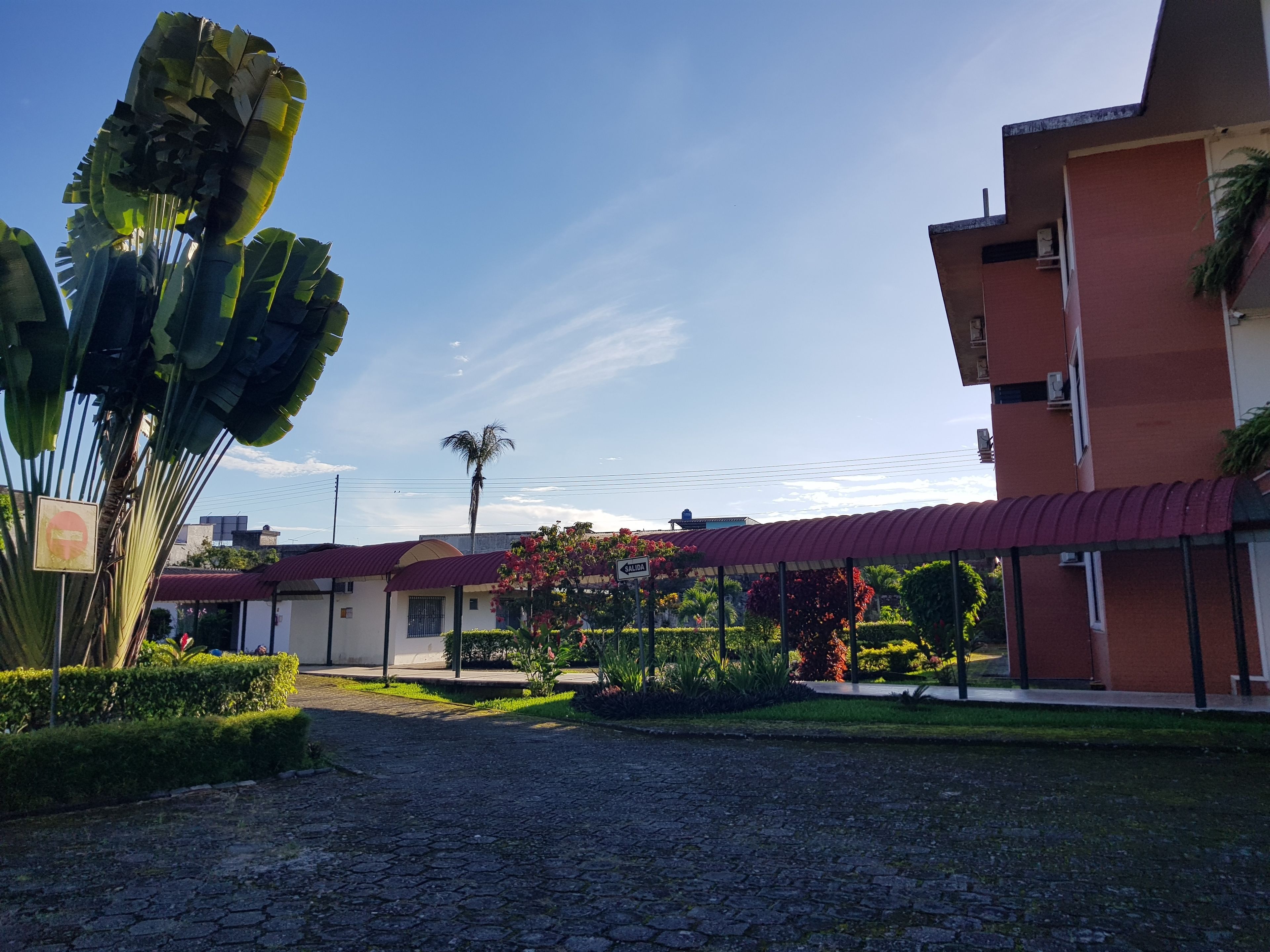 Un patio con pavimento de adoquines, un edificio con techo rojo y un letrero que indica 'SALIDA'.