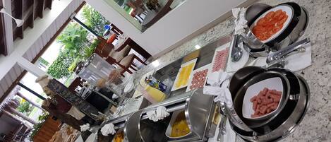 Una mesa de buffet con diversos alimentos, como carnes, quesos y pasteles, dispuestos sobre una encimera de mármol.