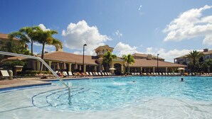 Une piscine avec des chaises longues et des palmiers.